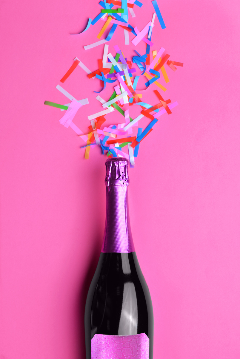 Bottle of Tasty Champagne with Confetti on Pink Background